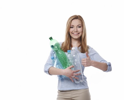 A young woman with long, straight, blonde hair and a cheerful expression is holding multiple clear plastic bottles, including a green glass bottle and several empty water bottles, against her chest. She is wearing a light grey, long-sleeved shirt with rolled-up sleeves and beige trousers. The background is plain white, creating a neutral setting. Her right hand is giving a thumbs-up gesture, and she appears to be in good spirits. The image emphasizes the importance of waste collection and recycling, aligning with rubbish removal services provided by Commercial Waste Removal Wandsworth, especially in the Wandsworth area. The bottles she holds represent typical waste items managed in commercial and domestic rubbish collection contexts, highlighting environmental awareness related to waste disposal practices. The lighting is bright and even, ensuring all details of her attire and the bottles are clearly visible. This image visually supports promotional content related to rubbish removal and waste recycling efforts in London’s Wandsworth region, subtly reinforcing local waste management services.